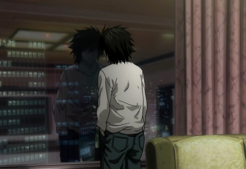 L looking out the window of a high-rise building, his reflection staring back at him.